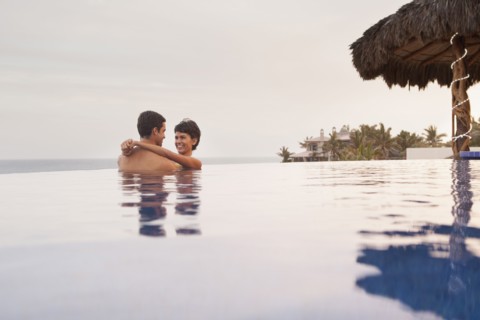 Hispanic couple hugging in swimming pool