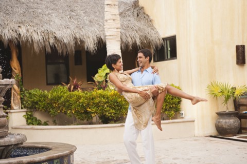 Hispanic man carrying wife in courtyard