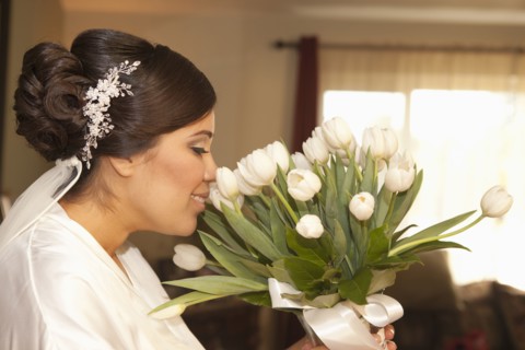 Hispanic bride smelling bouquet