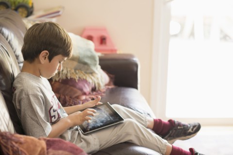 Hispanic boy on sofa using digital tablet