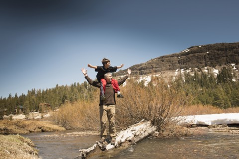 Boy sitting on father's shoulders in creek