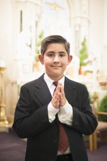 Hispanic boy with hands clasped in church