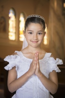 Hispanic girl with hands clasped in church