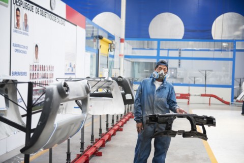 Worker holding machinery in manufacturing plant