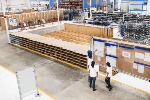 Workers reading bulletin board in manufacturing plant