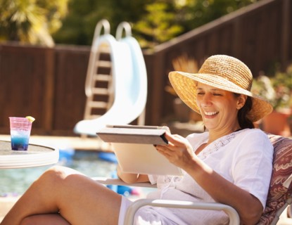 Hispanic woman using digital tablet by pool