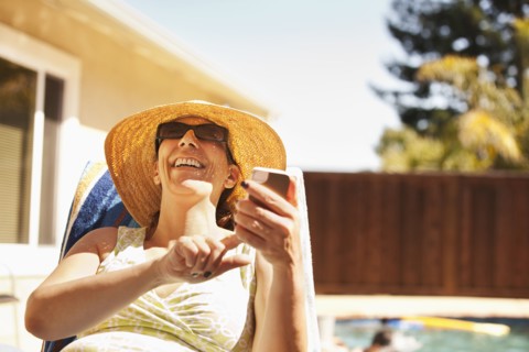Hispanic woman using cell phone by pool