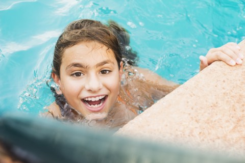 Mixed race girl swimming in pool