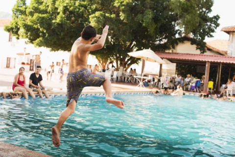 Mixed race boy jumping into pool