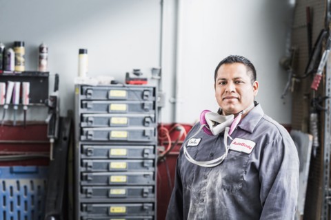 Hispanic mechanic standing in auto shop