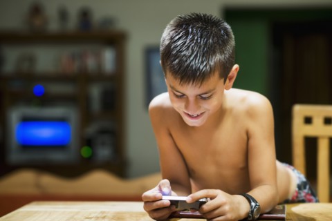 Hispanic boy using cell phone at table