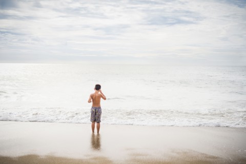 Hispanic boy standing in surf at beach