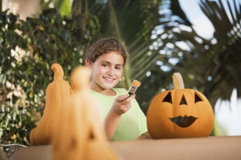 Hispanic girl decorating jack o'lantern
