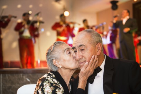 Hispanic couple kissing at wedding reception