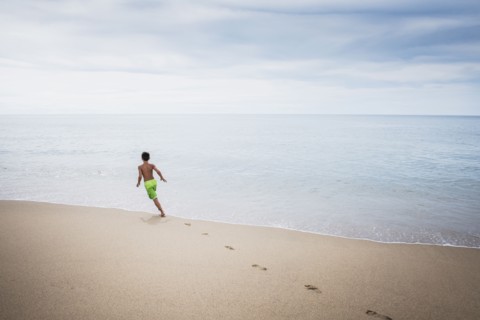 Mixed race boy playing on beach