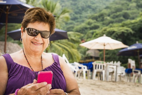 Senior woman using cell phone on beach