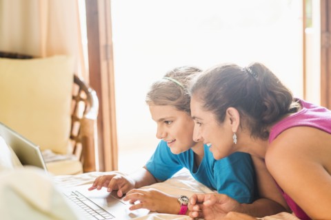 Mother and daughter using laptop at desk
