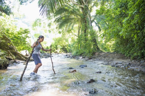 Hispanic woman crossing jungle stream