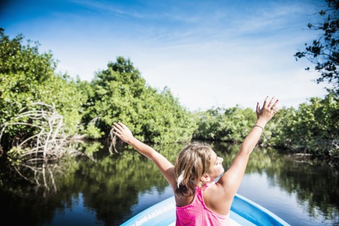 Mixed race girl sitting in canoe in still lake
