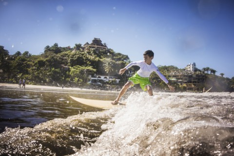 Mixed race boy surfing in ocean