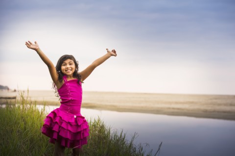 Hispanic girl cheering by still water