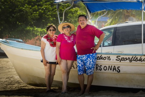 Hispanic friends smiling by boat on beach