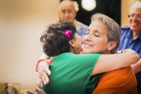 Hispanic women hugging in restaurant