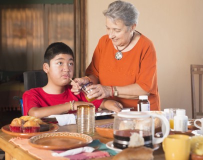 Hispanic woman helping grandson drink through straw