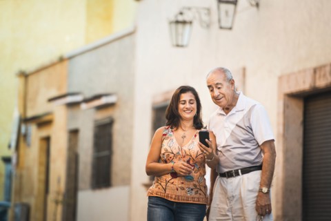 Hispanic father and daughter using cell phone in city
