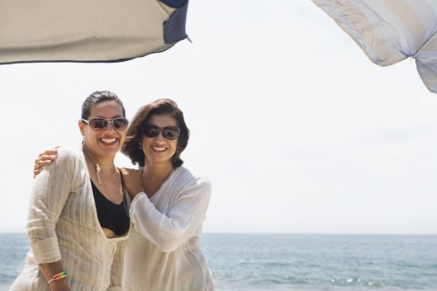 Hispanic women smiling together at beach