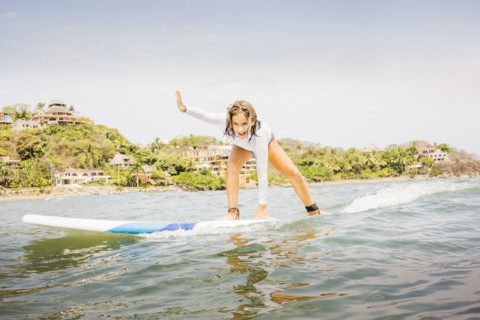 Mixed race girl surfing in waves