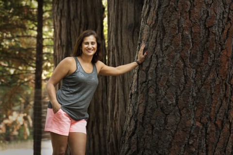 Hispanic woman leaning on enormous tree