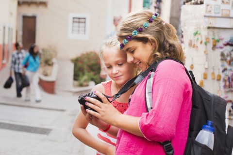 Girls looking at digital camera photographs on vacation