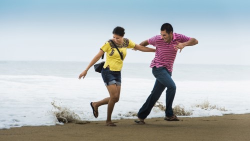 Hispanic couple playing near waves on beach
