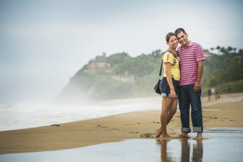 Hispanic couple hugging in waves on beach