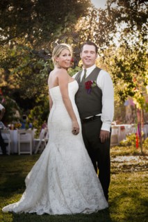 Caucasian bride and groom smiling at outdoor reception