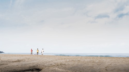 Children playing on beach under cloudy sky
