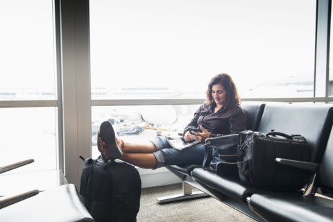 Hispanic woman texting on cell phone in airport