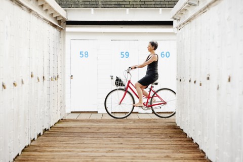 Older Caucasian woman riding bicycle on wooden dock