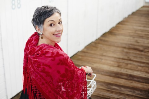 Older Caucasian woman with red shawl riding bicycle