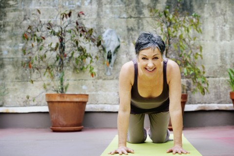 Older Caucasian woman practicing yoga in courtyard