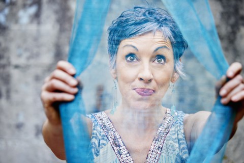 Older Caucasian woman examining sheer blue fabric