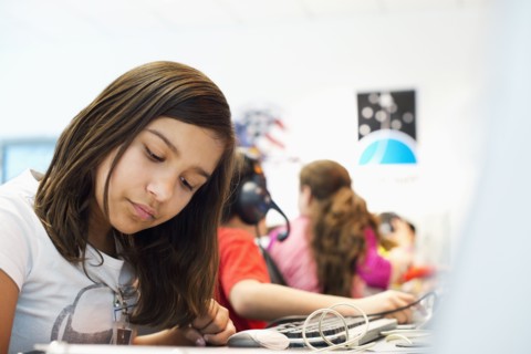 Hispanic student working at desk in classroom
