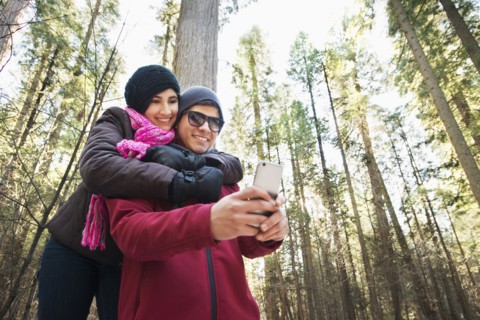 Hispanic teenage couple taking selfie in forest