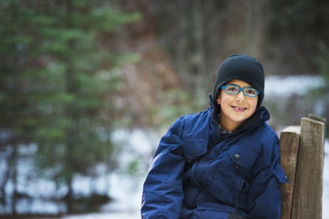 Hispanic boy sitting on chair in forest