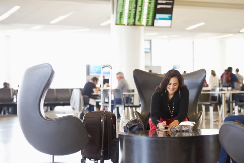 Hispanic businesswoman writing in airport waiting area