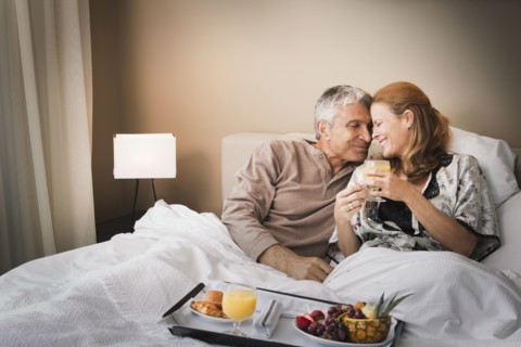 Smiling couple having breakfast in bed