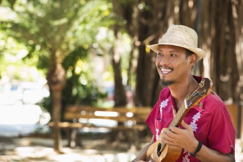 Hispanic musician playing ukulele in park