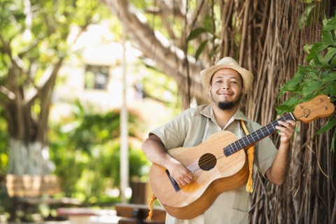 Hispanic musician playing guitar in park