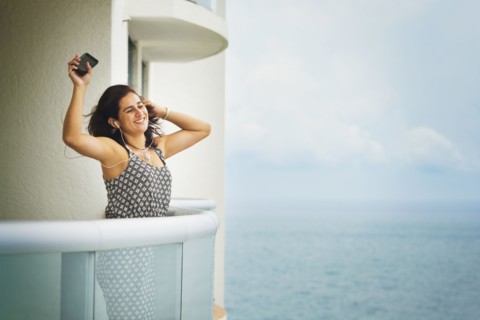 Hispanic woman dancing near ocean on hotel balcony